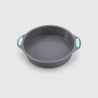 Gray silicone round cake pan with two small handles and mint-green pads, on a light gray background