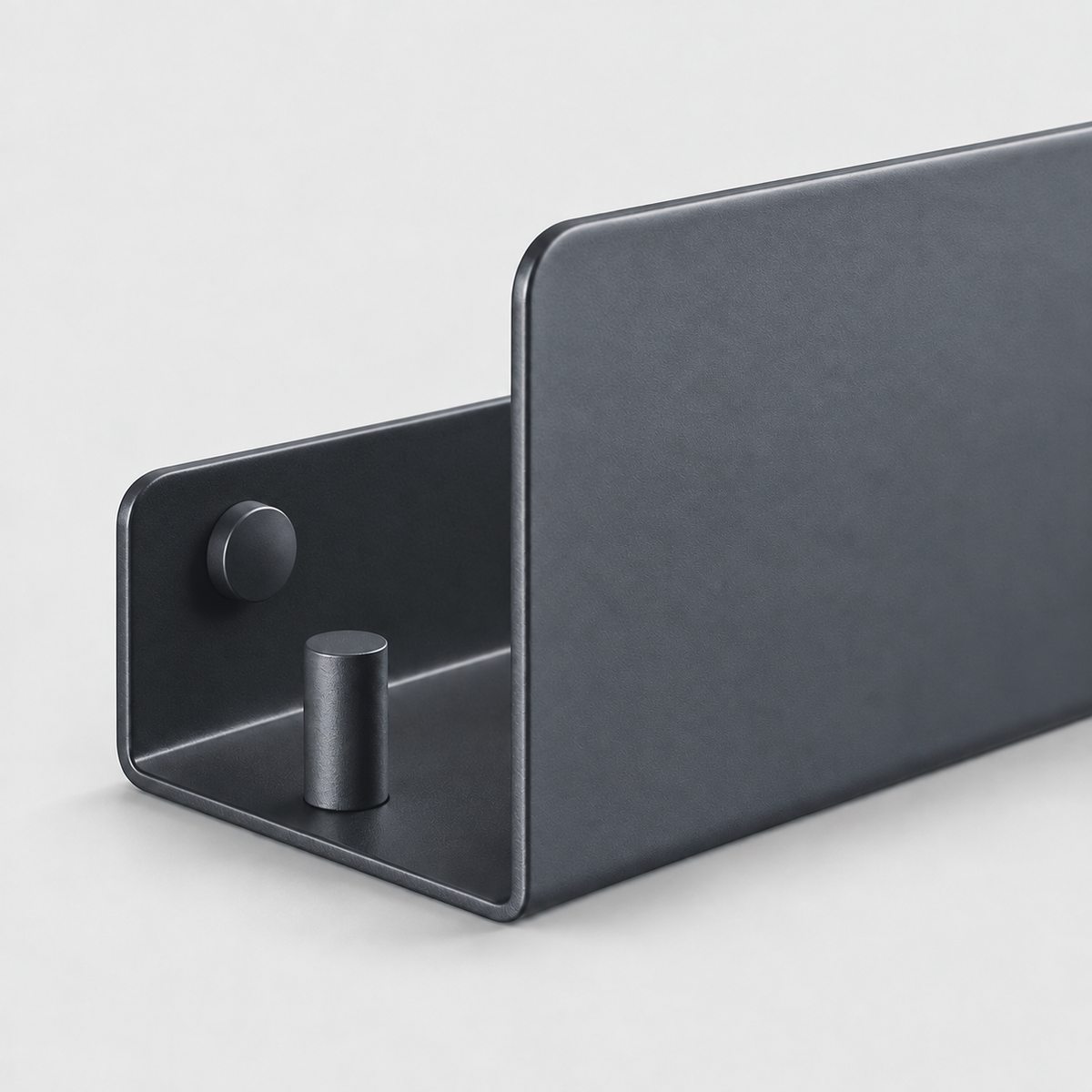 Close-up of the open end of a black aluminum shelf showing the short back plate, a screw head, the hook peg and the tall front lip