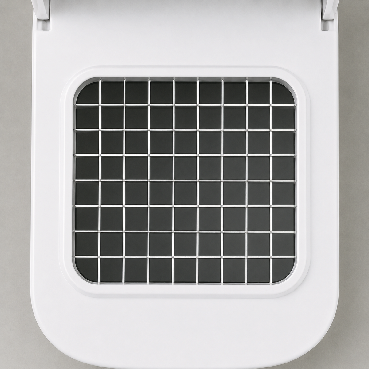 Close-up of the stainless steel blade grid set into the white top deck, an even lattice of square cells with dark openings.