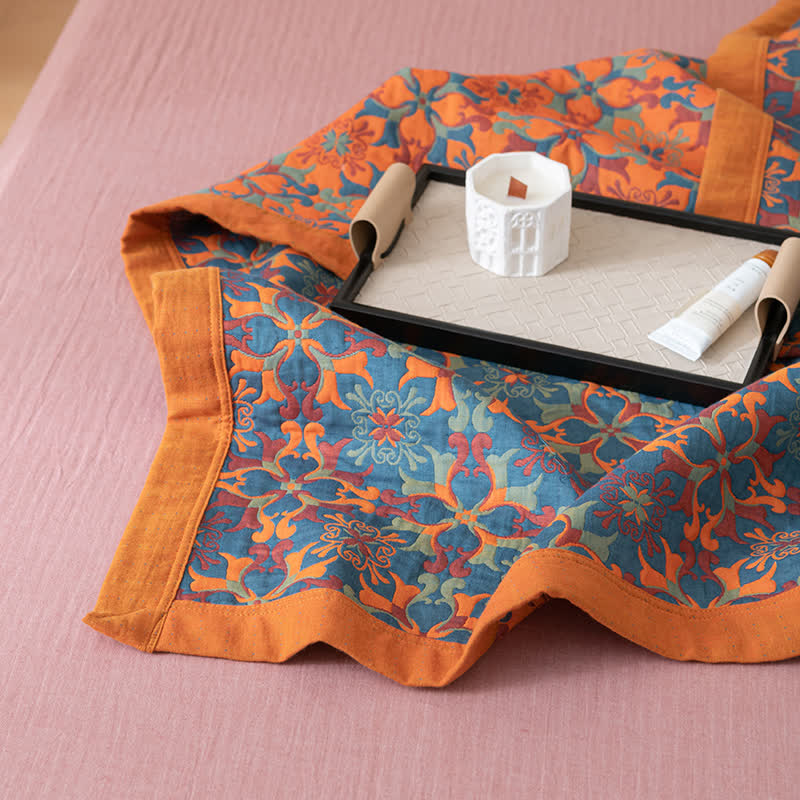 Corner of the quilt on a pink sheet, showing the blue pattern and the wide orange border