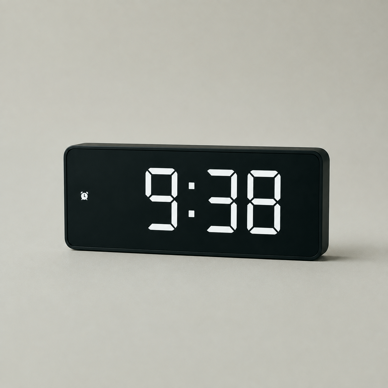 Black digital alarm clock with a flat black LED display on a plain studio background, showing 9:38