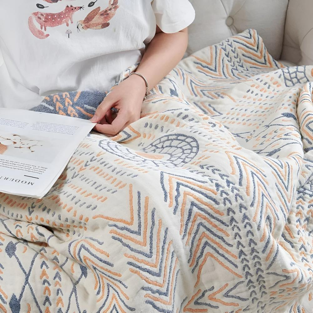 Woven cotton throw over a person's lap on a sofa, chevrons and dashes in orange and slate blue