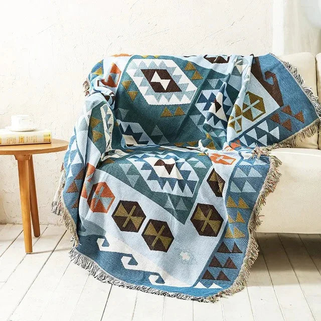 A blue jacquard throw with white diamonds and brown hexagons, draped over a cream couch