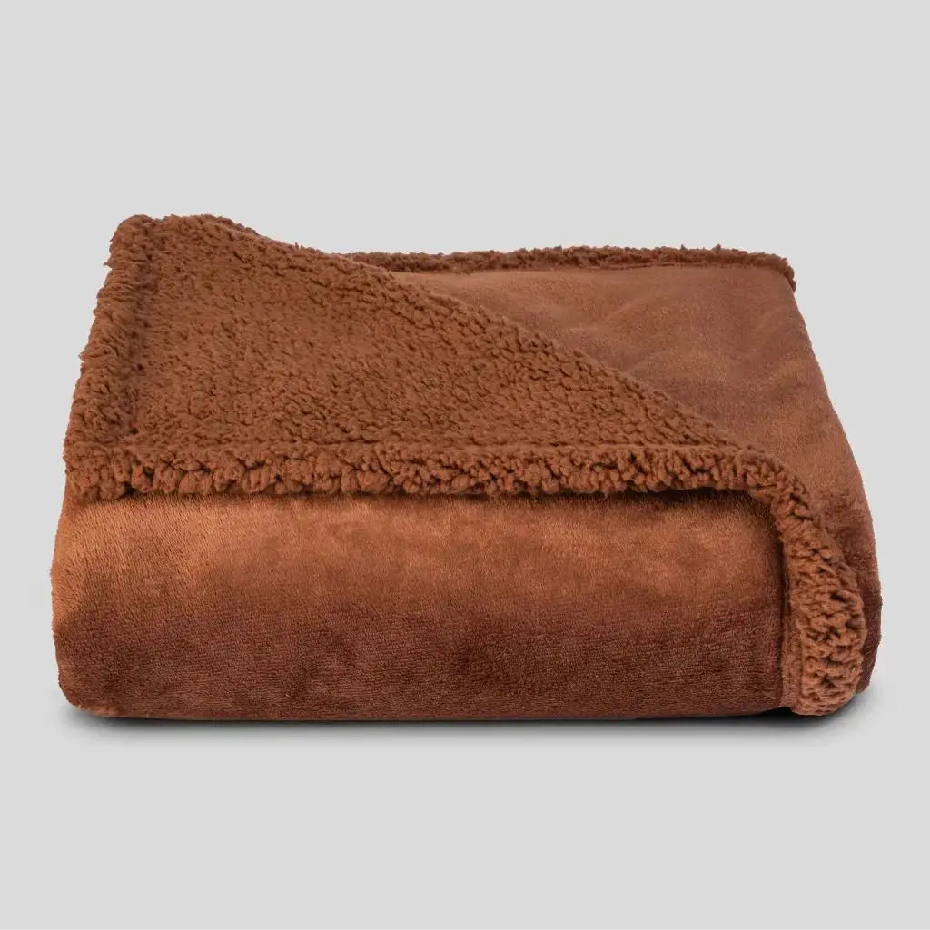 Rust brown waterproof blanket folded to show its plush face and sherpa reverse