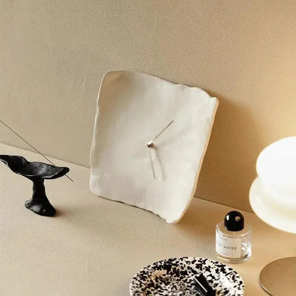 White crumpled resin wall clock propped at an angle against a beige wall, showing the rippled edge