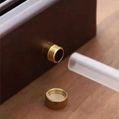 Close-up of the threaded drain outlet on the side of the tray with its knurled screw cap removed.