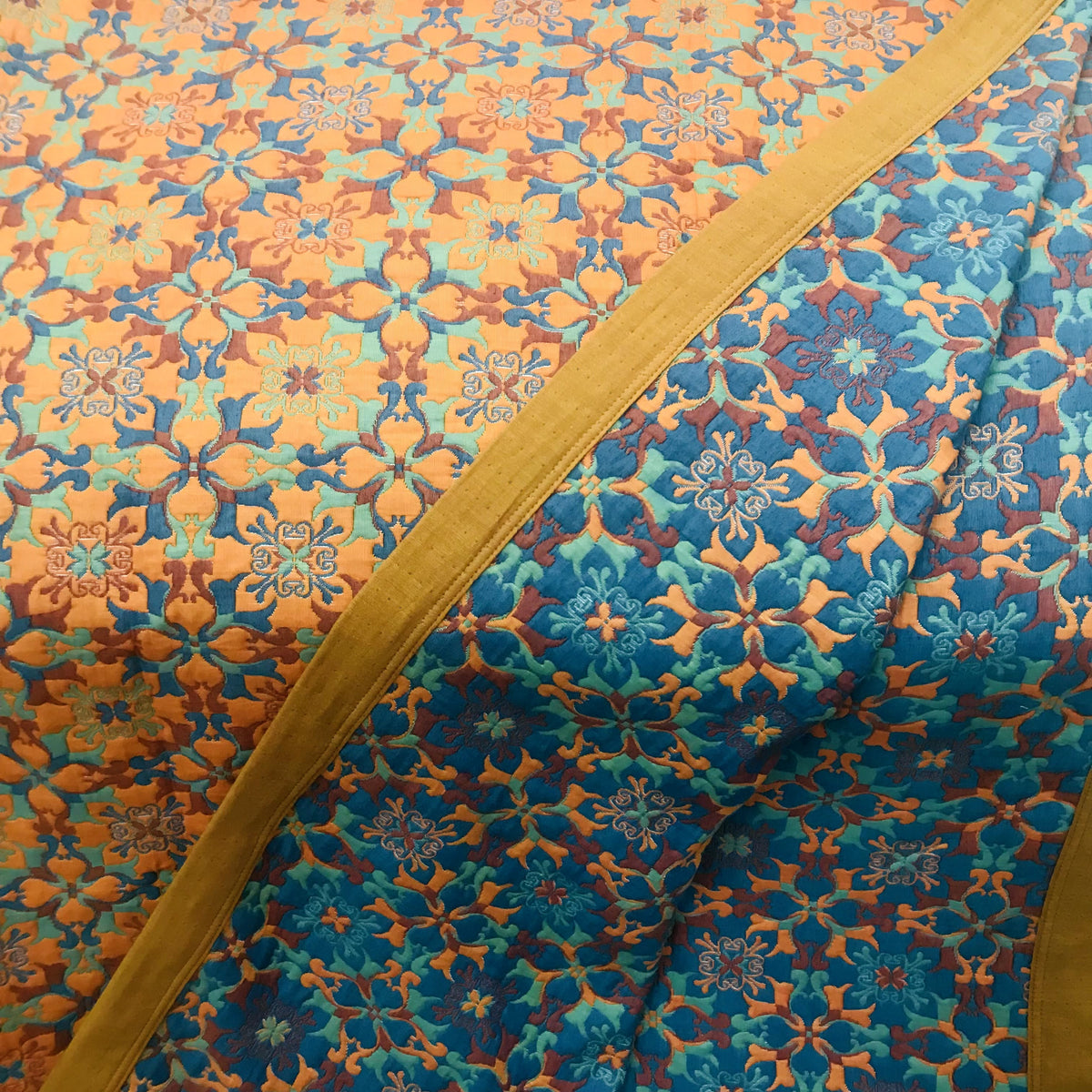 Close-up of the jacquard pattern, the orange reverse and the blue front meeting at the ochre orange border