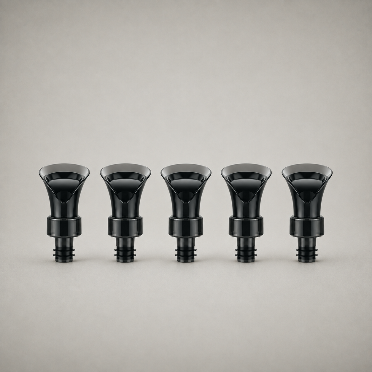 All five wine bottle stoppers in the set, in a row on a studio background