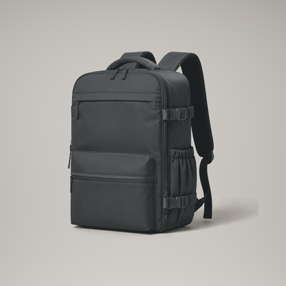 Black laptop backpack front three quarter view on a plain warm grey studio background