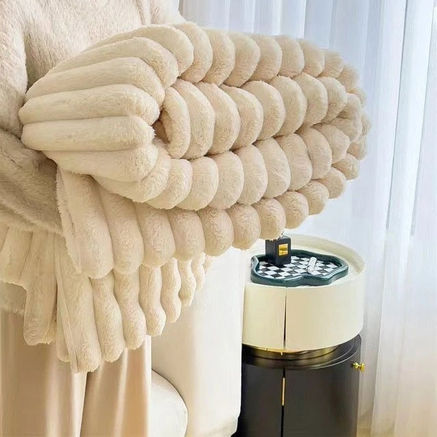 Cream faux rabbit fur throw rolled up in someone's arms, its pleats forming plump round rolls