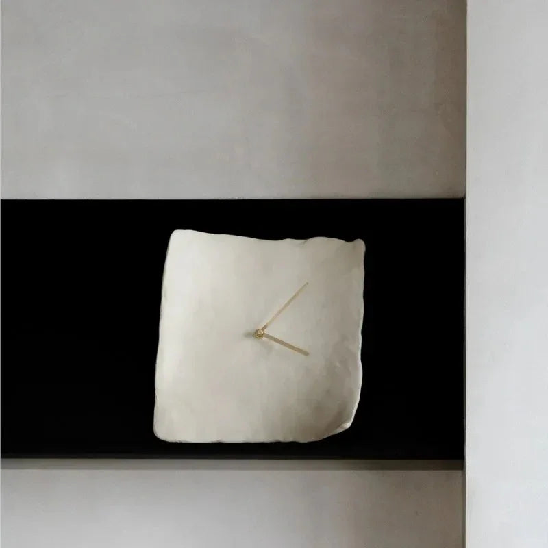 White crumpled resin wall clock seen straight on against a black band on a gray wall