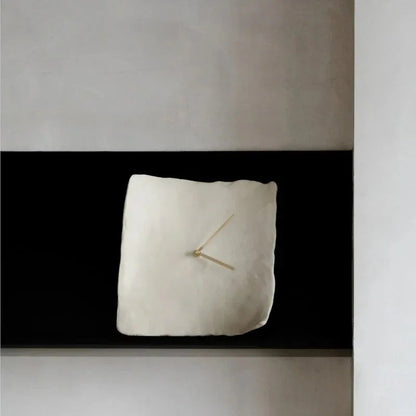 White crumpled resin wall clock seen straight on against a black band on a gray wall
