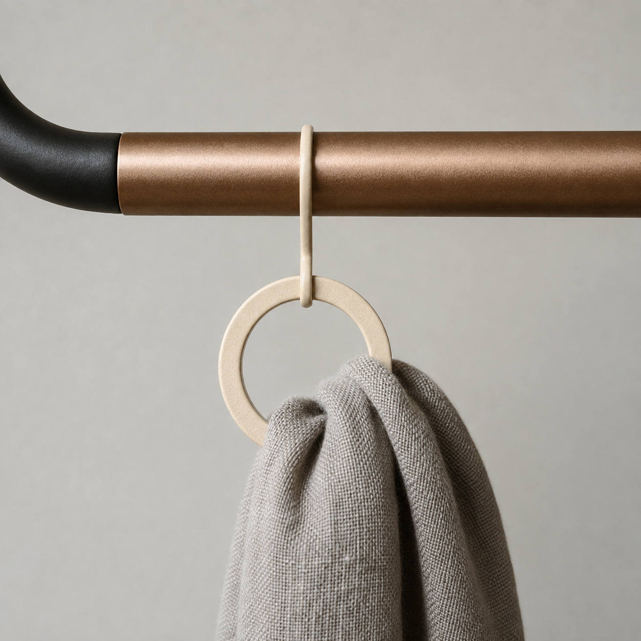 Close-up of one end of the crossbar where it meets the black frame, with a ring hanging from it and a grey scarf pulled through the ring.