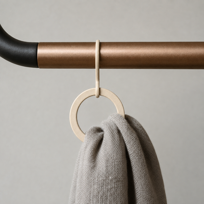 Close-up of one end of the crossbar where it meets the black frame, with a ring hanging from it and a grey scarf pulled through the ring.