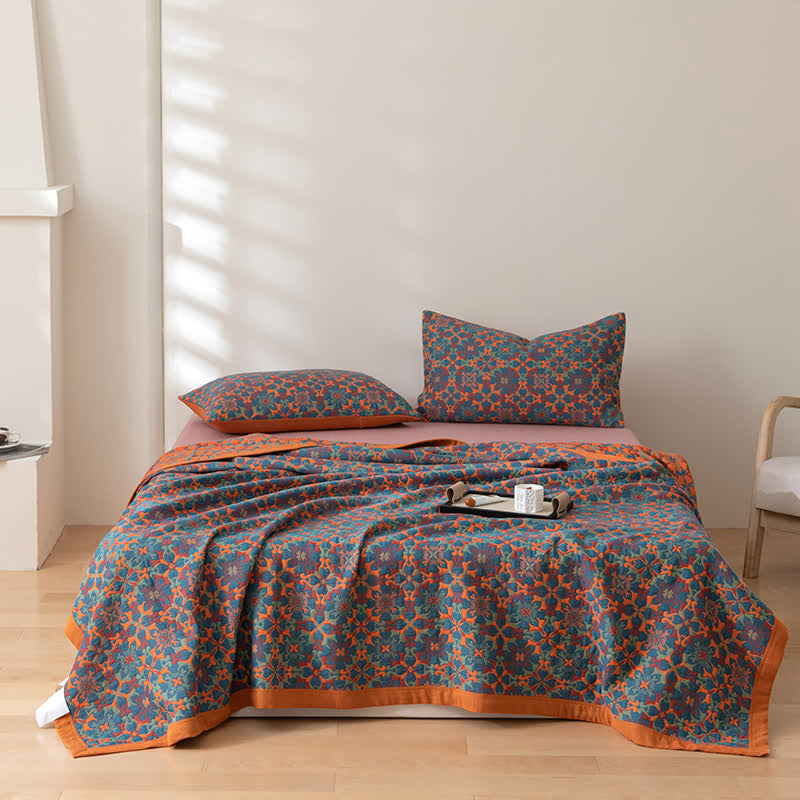 Quilt and two matching pillowcases in the orange and blue pattern on a made bed