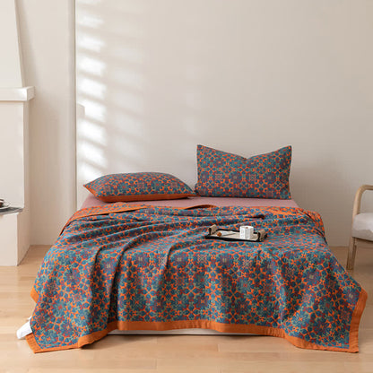 Quilt and two matching pillowcases in the orange and blue pattern on a made bed