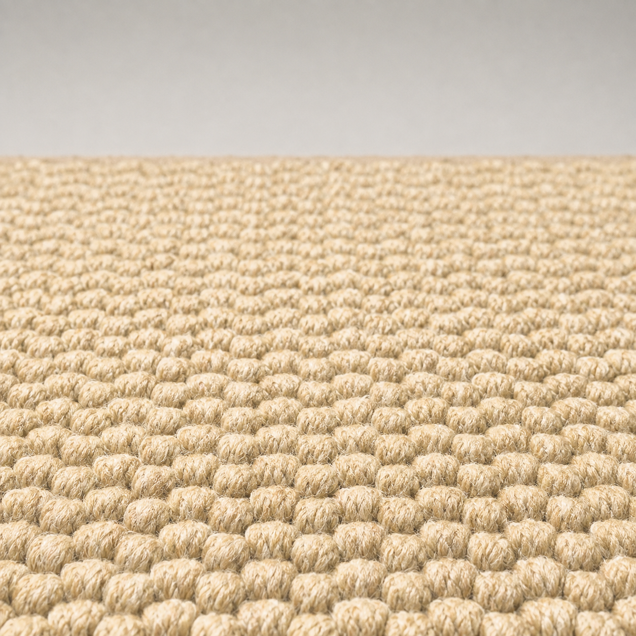 Close-up of the doormat surface, showing individual closed loops of marled cream and tan yarn, all the same height and packed tight so that no backing shows between them