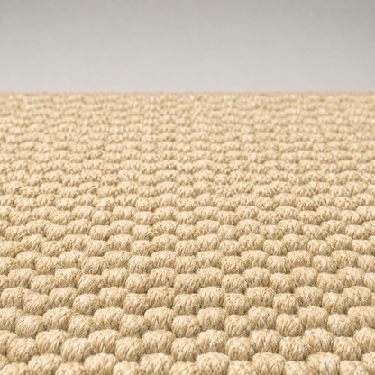 Close-up of the doormat surface, showing individual closed loops of marled cream and tan yarn, all the same height and packed tight so that no backing shows between them