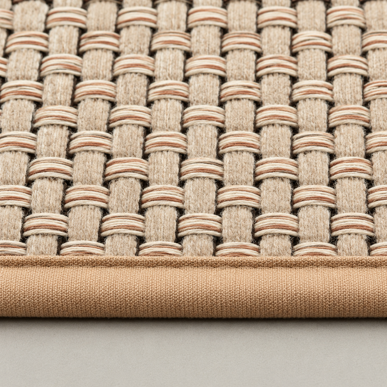 Close-up of the flat over-and-under weave and the bound camel edge tape of the beige rug