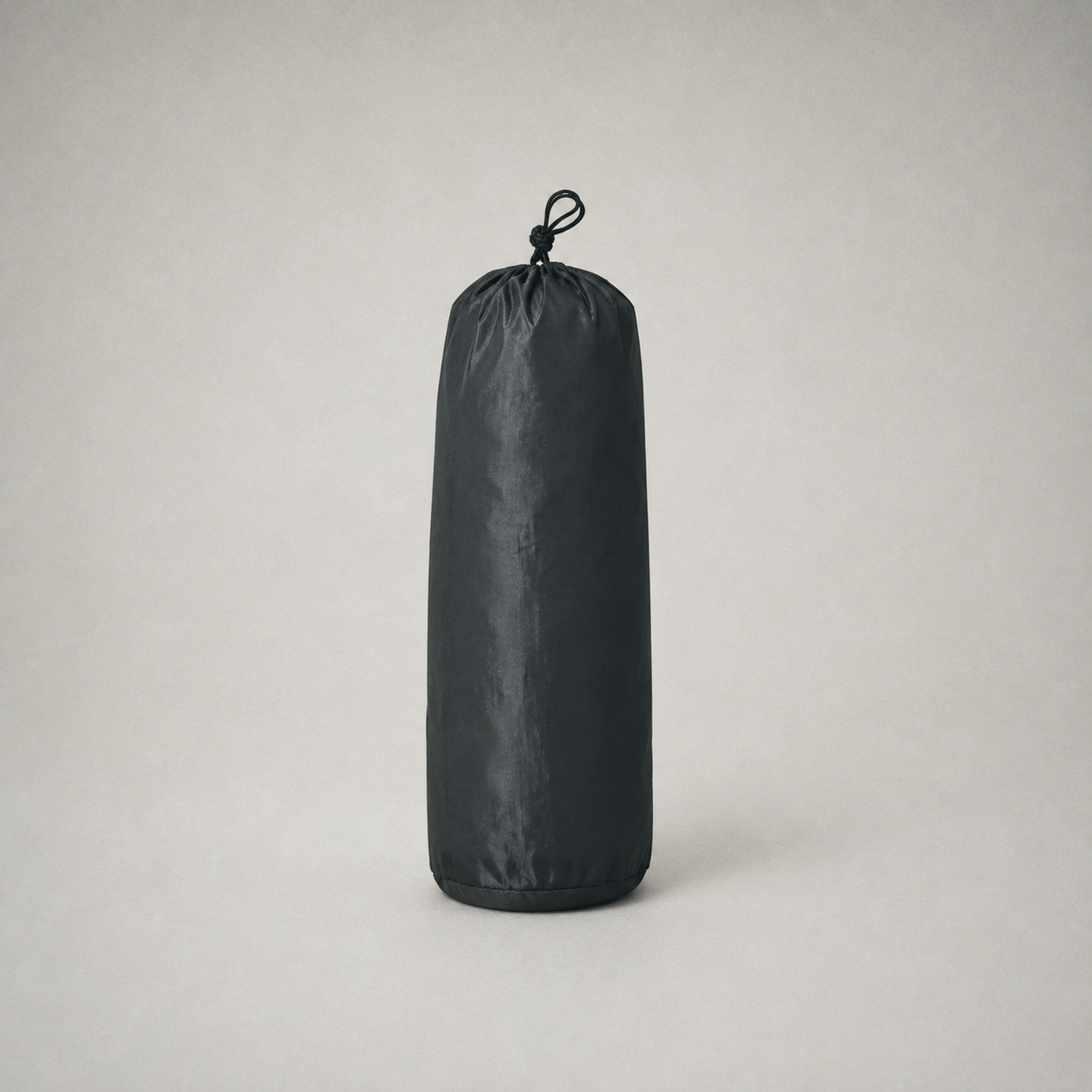 The tent packed into its black drawstring stuff sack on a plain grey studio background