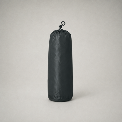 The tent packed into its black drawstring stuff sack on a plain grey studio background
