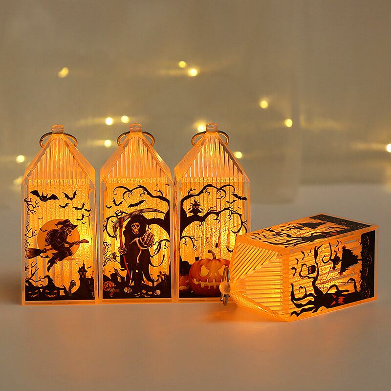 Three lit mini Halloween lanterns standing in a row with a fourth lying on its side in front