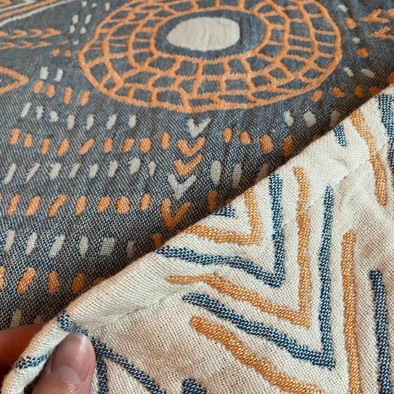 Close-up of the slate blue reverse with an orange sun ring and cream center, the cream face folded over beneath it