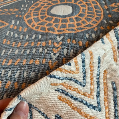 Close-up of the slate blue reverse with an orange sun ring and cream center, the cream face folded over beneath it