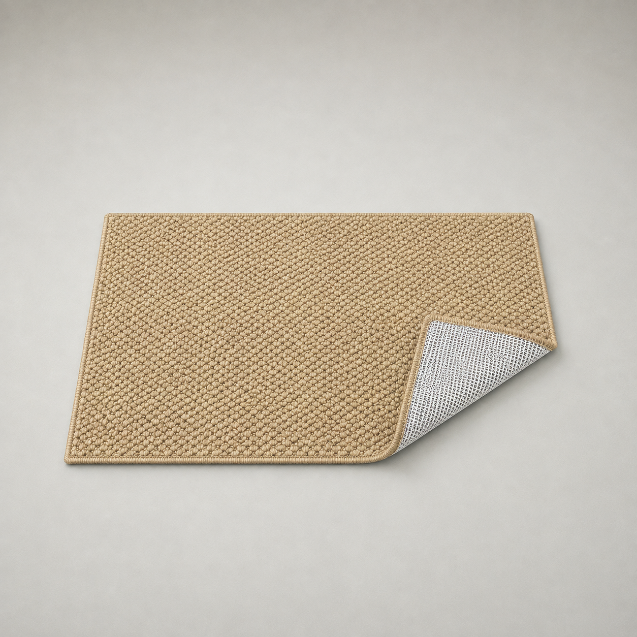 Doormat on a grey studio background with its near corner folded back, showing the off-white open mesh net over a dark charcoal base cloth on the underside and the tan overlock stitch along the edge