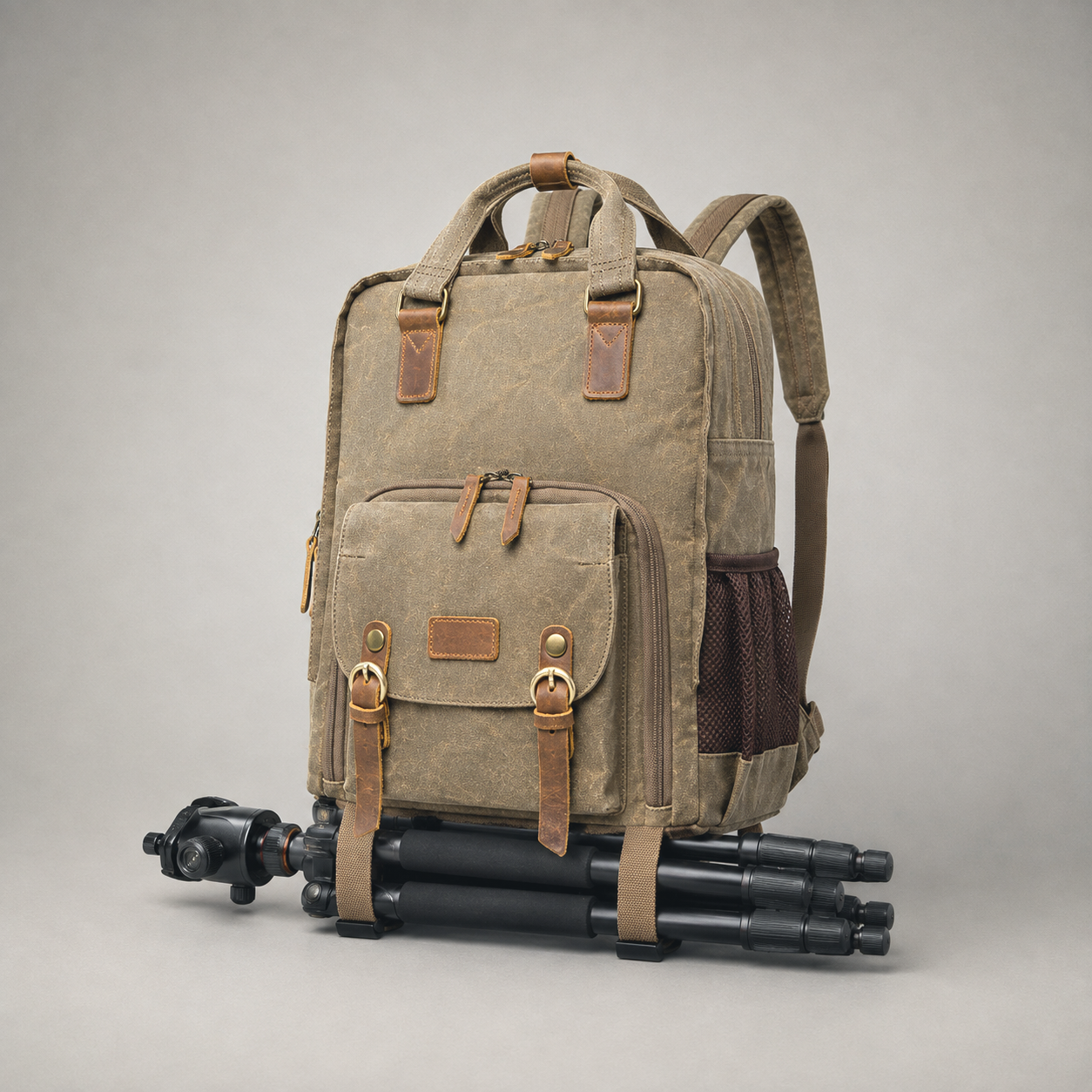 Camera backpack on a grey background with a folded tripod strapped under its base.