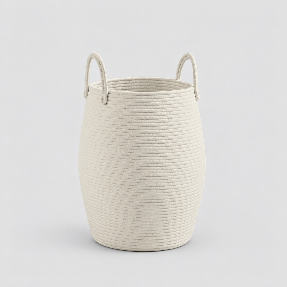 A white rope laundry hamper with two rope handles, standing empty on a light grey background.