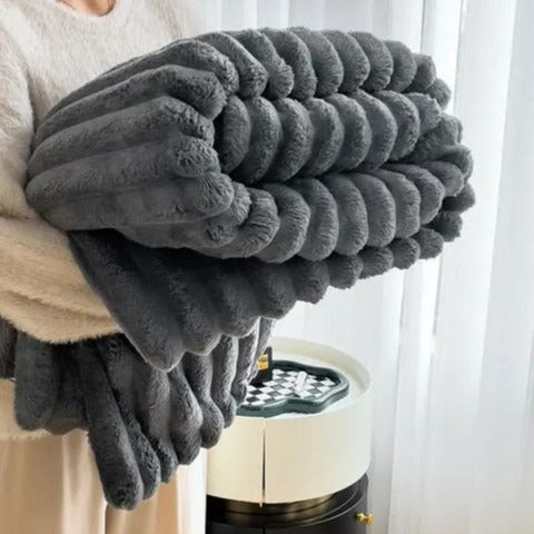 Charcoal faux rabbit fur throw rolled up in someone's arms, its pleats forming plump round rolls