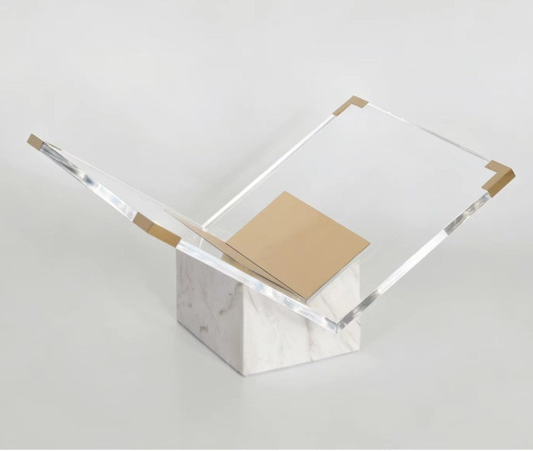 White and gold marble stand with gold-toned corner caps and a folded gold-toned plate in its clear acrylic V
