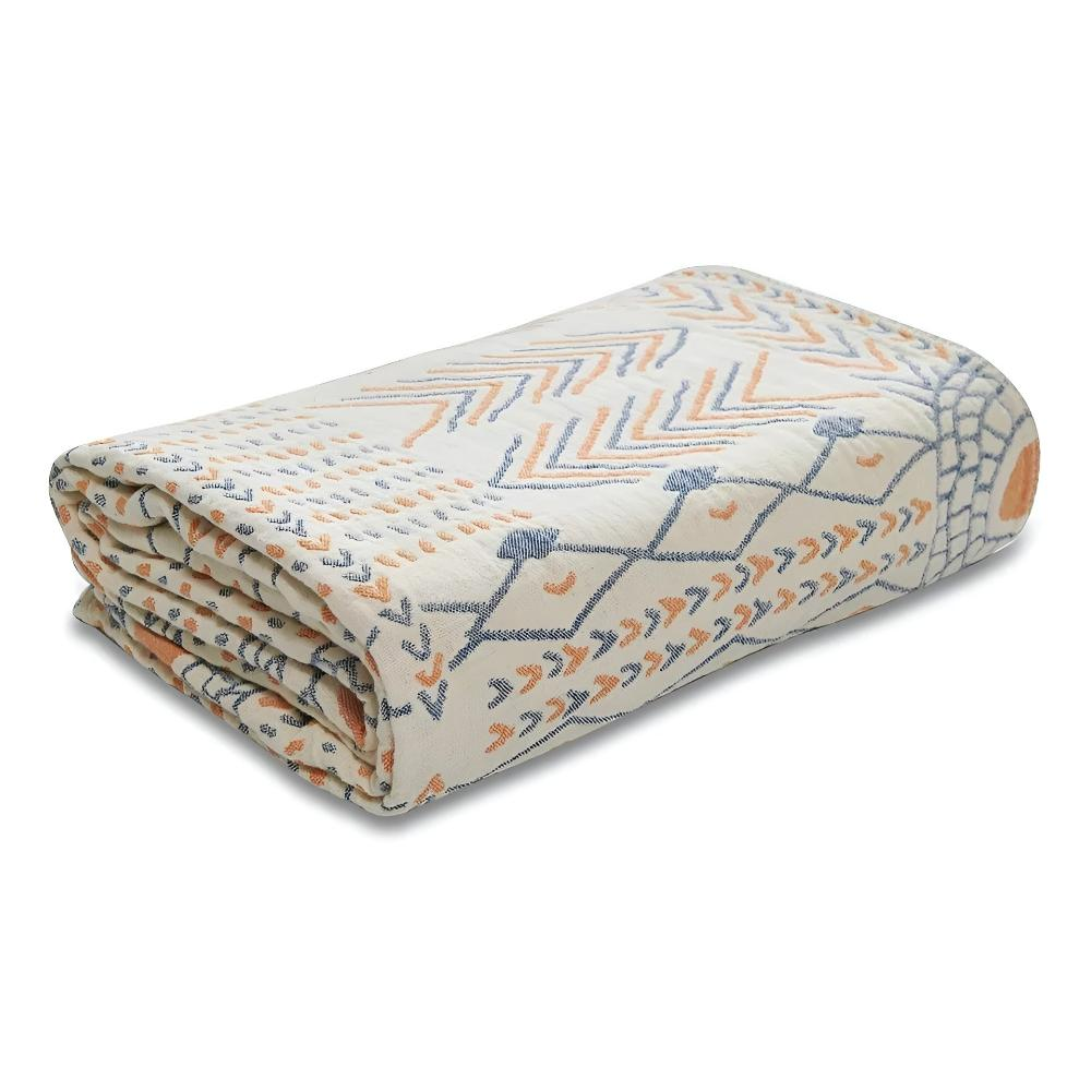 Reversible boho blanket folded on a white background, cream with slate blue lattice lines and orange arrows