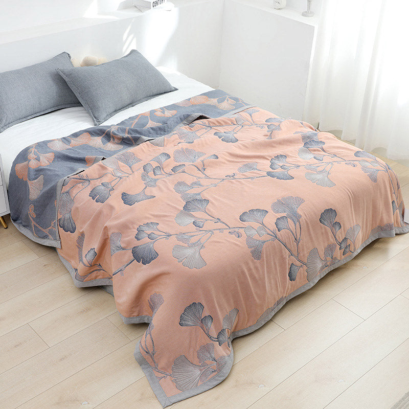Peach ginkgo leaf gauze quilt spread over a bed, with its slate gray reverse and peach leaves folded back at the pillows
