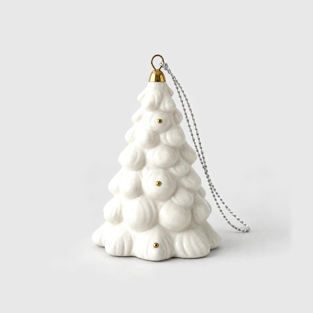 White ceramic Christmas tree ornament in the Frosted style, covered in rounded snow clumps with a small gold cap, on a light gray background