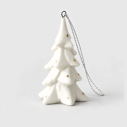 Tall slim white ceramic Christmas tree ornament in the Spruce style with drooping snowy branches and small gold flecks, on a light gray background