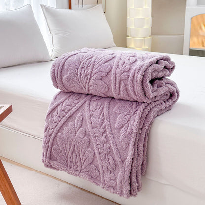 Purple embossed fleece blanket folded and rolled on a bed
