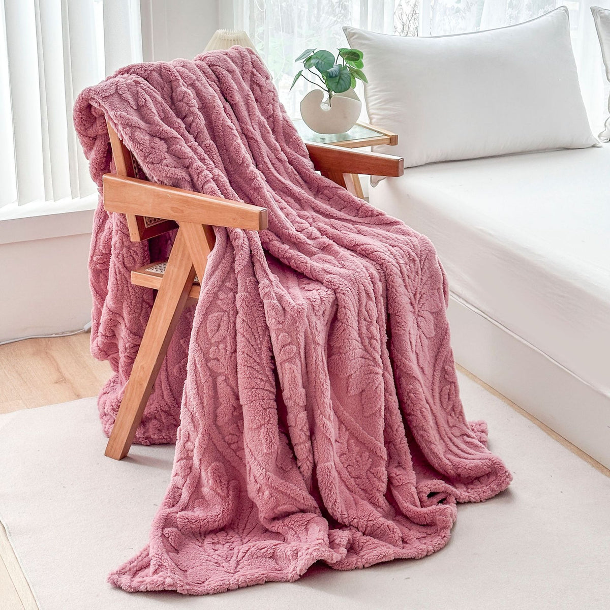 Pink fleece blanket draped over a wooden armchair