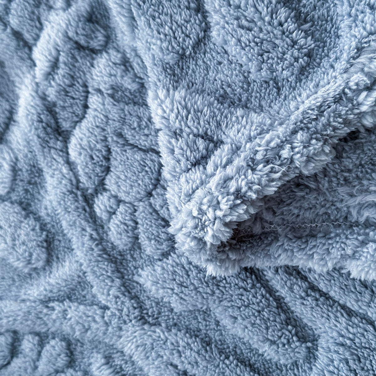 Close-up of the raised pattern and curly pile on the blue fleece blanket