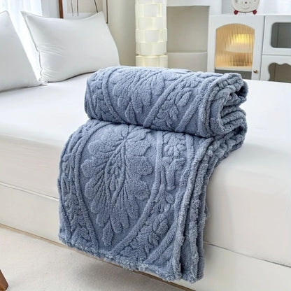 Blue embossed fleece blanket folded and rolled on a bed