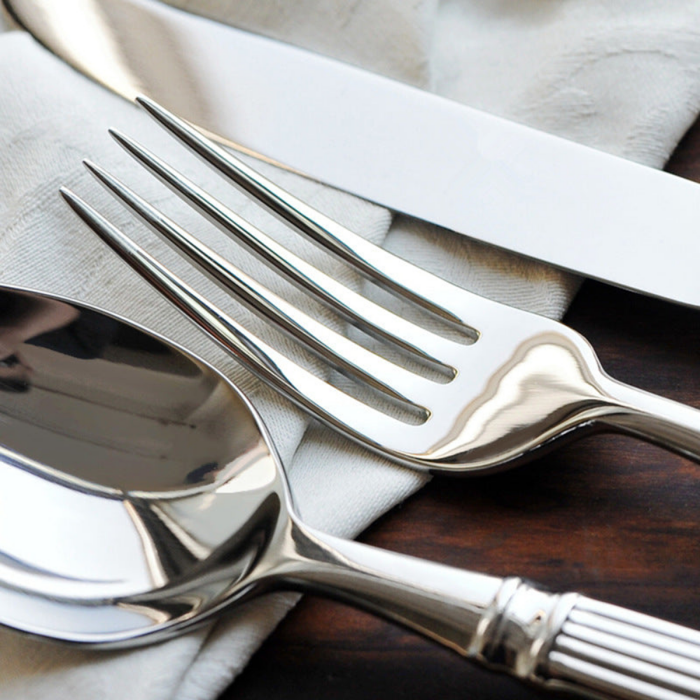 Close up of the fork tines, the knife blade and the spoon bowl in mirror polished stainless steel