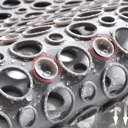 Close view of the wet shower mat showing the raised collar around each drainage hole