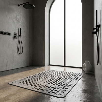 Beige non slip shower mat with drainage holes on the wet floor of a concrete walk-in shower