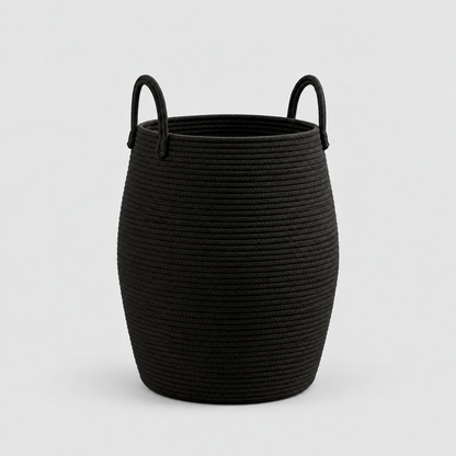 A black rope laundry hamper with two rope handles, standing empty on a light grey background.