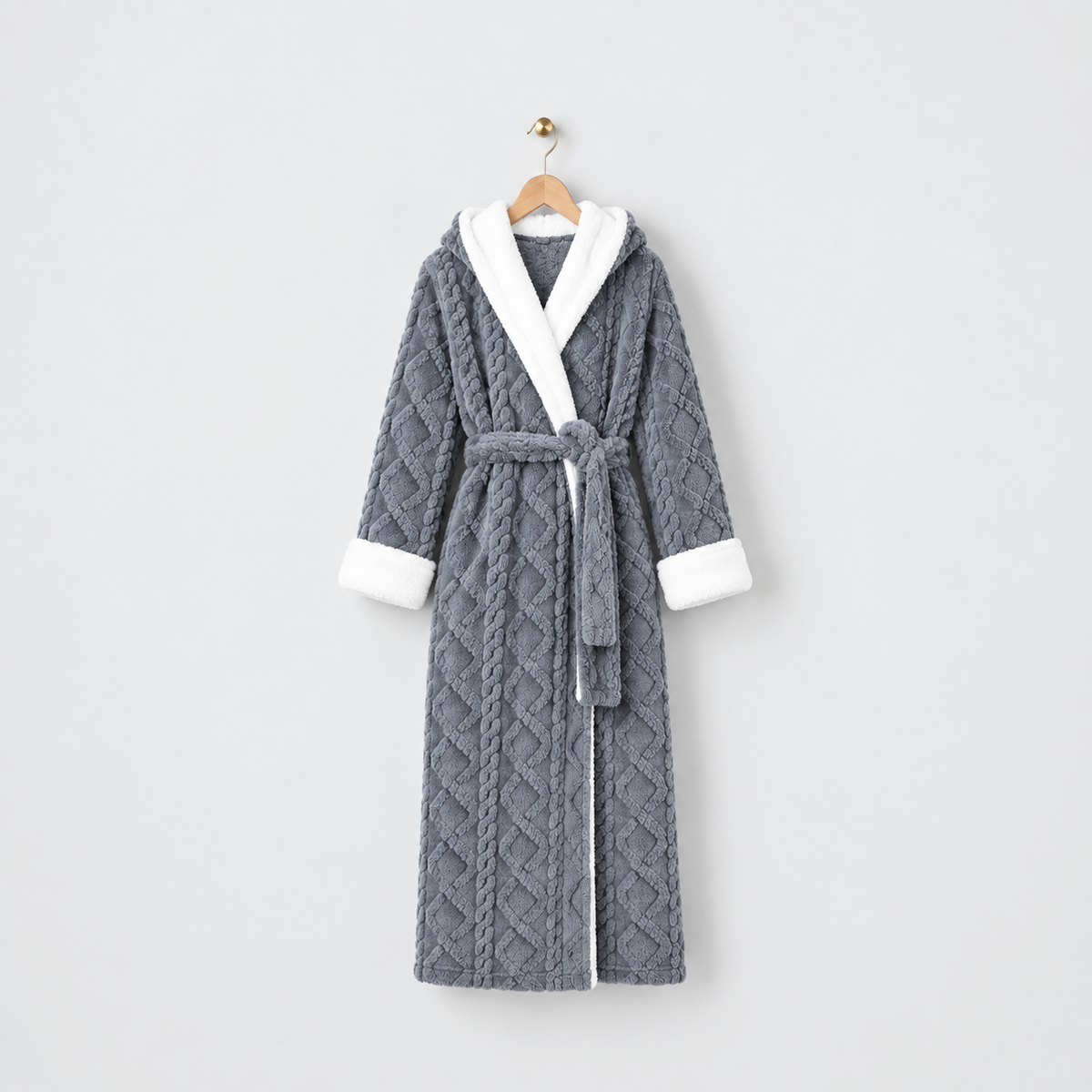 Long gray hooded plush bathrobe with a raised cable and diamond pattern, white cuffs and a tied belt, on a wooden hanger against a light gray wall
