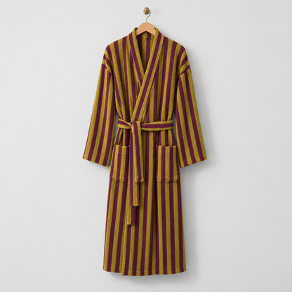 Long mustard and burgundy striped fleece bathrobe with a tie belt, hanging on a wooden hanger on a light gray wall