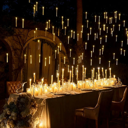 Floating LED candles massed above a long garden banquet table at night