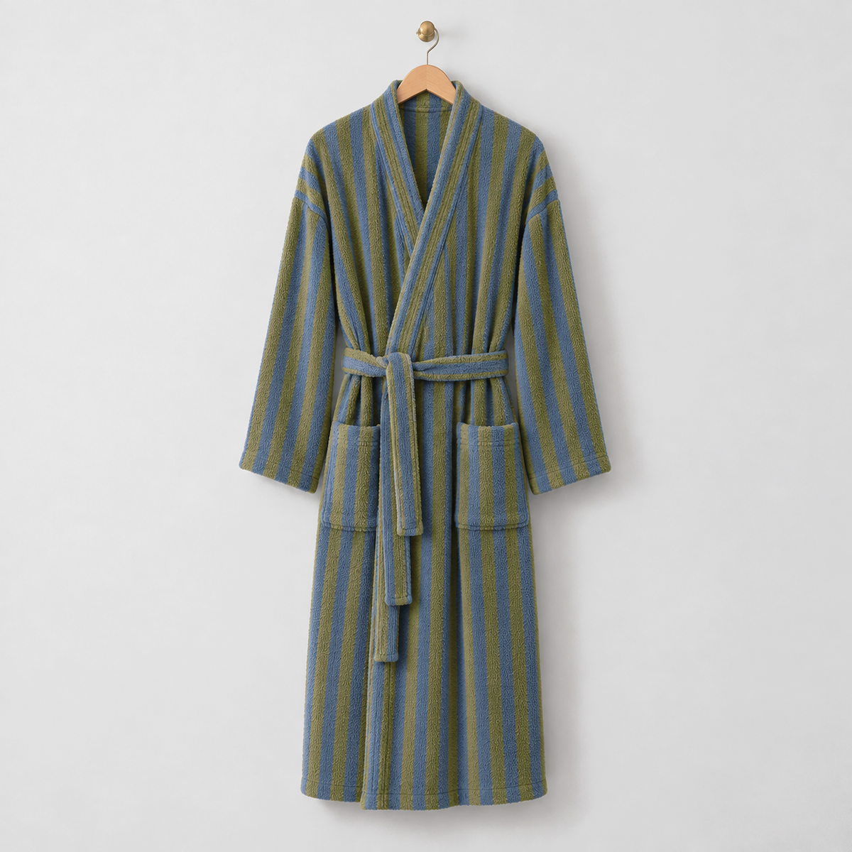 Long olive and blue striped fleece bathrobe with a kimono collar, tie belt and patch pockets, hanging on a wooden hanger on a light gray wall