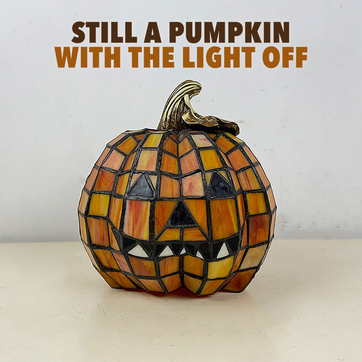 Mosaic pumpkin lamp switched off in daylight with the words Still a pumpkin with the light off